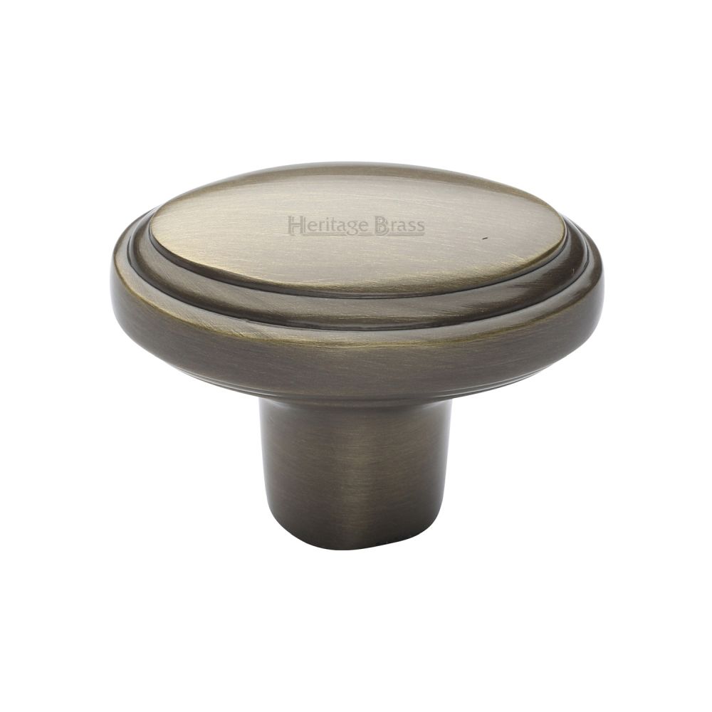 This is an image of a Heritage Brass - Cabinet Knob Stepped Oval Design 41mm Antique Brass Finish, c3975-at that is available to order from T.H Wiggans Ironmongery in Kendal.
