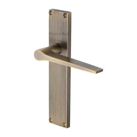 This is an image of a Heritage Brass - Gio Reeded Lever Latch Antique Brass finish, rr4710-at that is available to order from T.H Wiggans Ironmongery in Kendal.