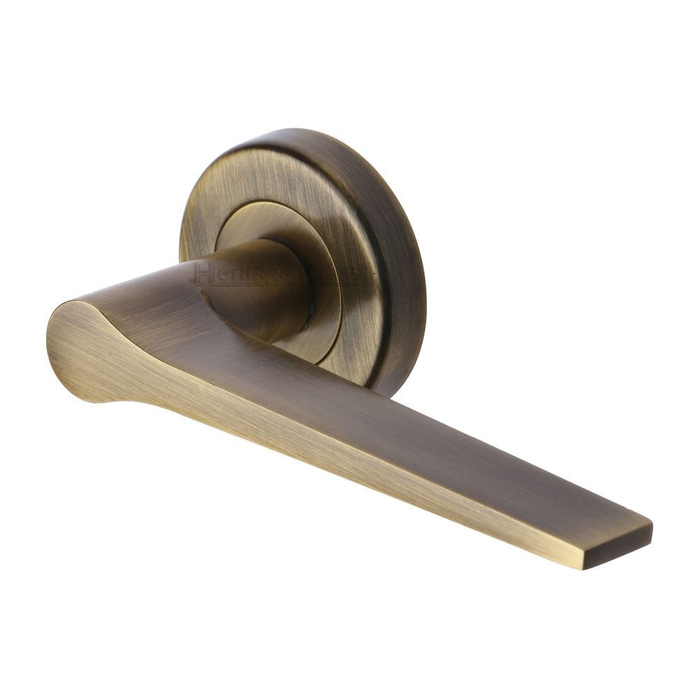 This is an image of a Heritage Brass - Door Handle Lever on Rose Gio Design Antique Brass Finish, v4189-at that is available to order from T.H Wiggans Ironmongery in Kendal.