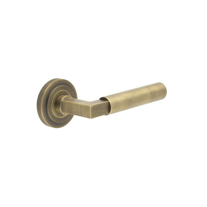 This is an image showing the Frelan - Westminster Door Handle on Stepped Rose Antique Brass available to order from T.H. Wiggans Ironmongery in Kendal