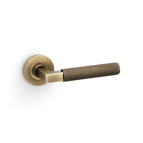 This is an image showing Alexander & Wilks Hurricane Knurled Lever on Round Rose - Antique Brass aw200ab available to order from T.H Wiggans Ironmongery in Kendal, quick delivery and discounted prices.