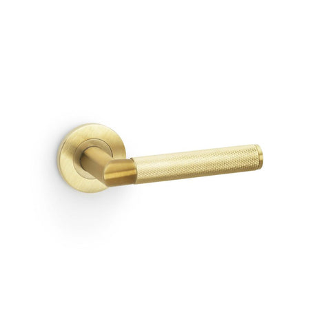 This is an image showing Alexander & Wilks Harrier Knurled Lever on Round Rose - Satin Brass PVD aw210sbpvd available to order from T.H Wiggans Ironmongery in Kendal, quick delivery and discounted prices.
