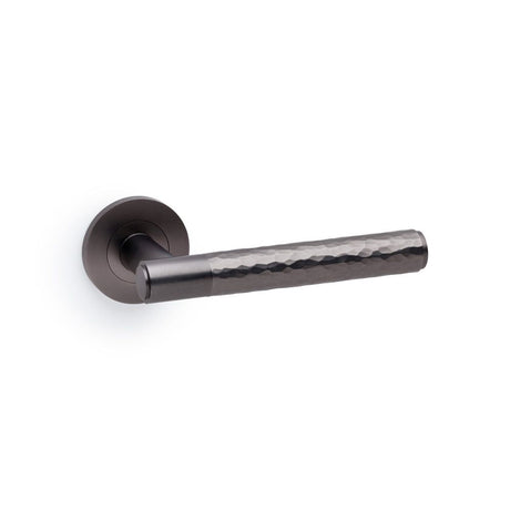 This is an image showing Alexander & Wilks Spitfire Hammered Lever on Round Rose - Dark Bronze aw223dbz available to order from T.H Wiggans Ironmongery in Kendal, quick delivery and discounted prices.