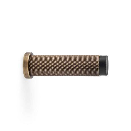 This is an image showing Alexander & Wilks Brunel Knurled Door Stop - Antique Brass aw600-75-ab available to order from T.H Wiggans Ironmongery in Kendal, quick delivery and discounted prices.