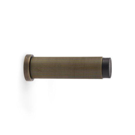 This is an image showing Alexander & Wilks Reeded Projection Door Stop - Antique Brass aw602-75-ab available to order from T.H Wiggans Ironmongery in Kendal, quick delivery and discounted prices.