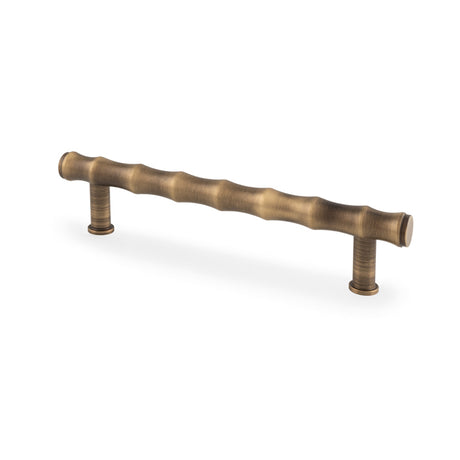 This is an image showing Alexander & Wilks Crispin Bamboo T-bar Cupboard Pull Handle - Antique Brass - 128mm Centres aw809b-128-ab available to order from T.H Wiggans Ironmongery in Kendal, quick delivery and discounted prices.