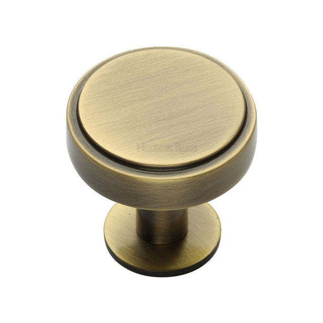 This is an image of a Heritage Brass - Cabinet Knob Stepped Disc Design with Rose 32mm Antique Brass Fini, c3954-32-at that is available to order from T.H Wiggans Ironmongery in Kendal.
