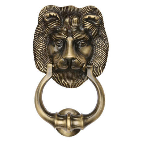 This is an image of a Heritage Brass - Lion Knocker Antique Brass Finish, k1210-at that is available to order from T.H Wiggans Ironmongery in Kendal.