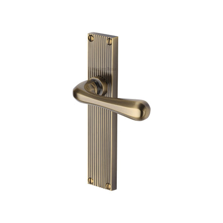 This is an image of a Heritage Brass - Charlbury Reeded Lever Latch Antique Brass finish, rr3010-at that is available to order from T.H Wiggans Ironmongery in Kendal.