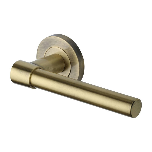 This is an image of a Heritage Brass - Door Handle Lever on Rose Phoenix Design Antique Brass Finish, rs2017-at that is available to order from T.H Wiggans Ironmongery in Kendal.