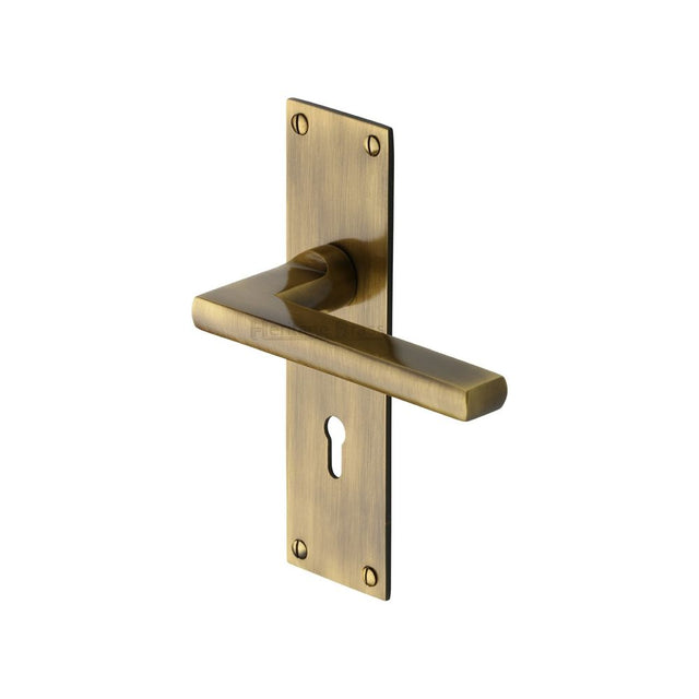 This is an image of a Heritage Brass - Door Handle Lever Lock Trident Design Antique Brass Finish, tri1300-at that is available to order from T.H Wiggans Ironmongery in Kendal.