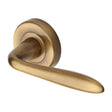 This is an image of a Heritage Brass - Door Handle Lever Latch on Round Rose Sutton Design Antique Brass, v1750-at that is available to order from T.H Wiggans Ironmongery in Kendal.