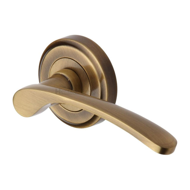 This is an image of a Heritage Brass - Door Handle Lever Latch on Round Rose Sophia Design Antique Brass, v1900-at that is available to order from T.H Wiggans Ironmongery in Kendal.