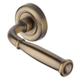 This is an image of a Heritage Brass - Door Handle Lever Latch on Round Rose Lincoln Design Antique Brass, v1938-at that is available to order from T.H Wiggans Ironmongery in Kendal.