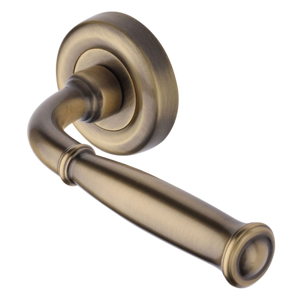 This is an image of a Heritage Brass - Door Handle Lever Latch on Round Rose Lincoln Design Antique Brass, v1938-at that is available to order from T.H Wiggans Ironmongery in Kendal.