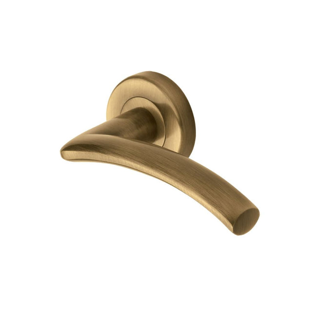 This is an image of a Heritage Brass - Door Handle Lever Latch on Round Rose Centaur Design Antique Brass, v3490-at that is available to order from T.H Wiggans Ironmongery in Kendal.