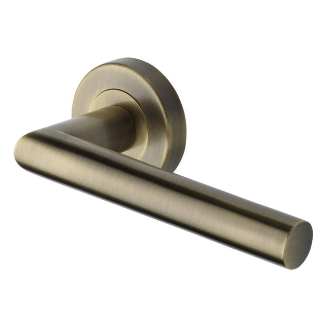 This is an image of a Heritage Brass - Door Handle Lever Latch on Round Rose Athena Design Antique Brass, v3840-at that is available to order from T.H Wiggans Ironmongery in Kendal.