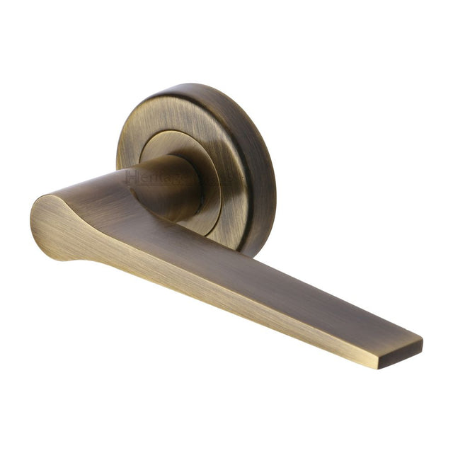 This is an image of a Heritage Brass - Door Handle Lever on Rose Gio Design Antique Brass Finish, v4189-at that is available to order from T.H Wiggans Ironmongery in Kendal.