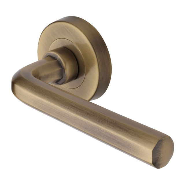 This is an image of a Heritage Brass - Door Handle Lever Latch on Round Rose Octave Design Antique Brass, v4545-at that is available to order from T.H Wiggans Ironmongery in Kendal.