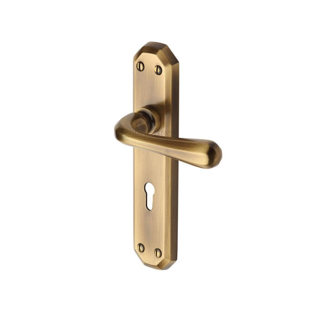 This is an image of a Heritage Brass - Door Handle Lever Lock Charlbury Design Antique Brass Finish, v7050-at that is available to order from T.H Wiggans Ironmongery in Kendal.