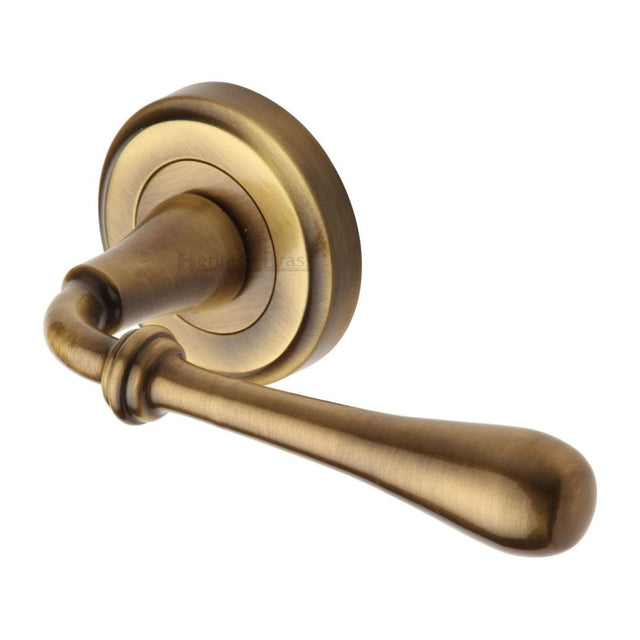 This is an image of a Heritage Brass - Door Handle Lever Latch on Round Rose Roma Design Antique Brass Fi, v7155-at that is available to order from T.H Wiggans Ironmongery in Kendal.
