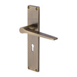 This is an image of a Heritage Brass - Gio Lever Lock Door Handle on 200mm Plate Antique Brass finish, vt8100-at that is available to order from T.H Wiggans Ironmongery in Kendal.