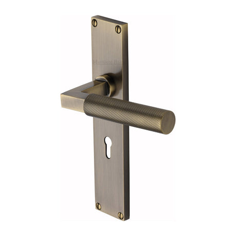 This is an image of a Heritage Brass - Bauhaus Knurled Lever Lock Door Handle on 200mm Plate Antique Brass finish, vt9300-at that is available to order from T.H Wiggans Ironmongery in Kendal.