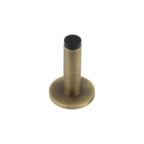 This is an image showing the Frelan - Burlington Plain Wall Mounted Door Stops Plain Rose Antique Brass available to order from T.H. Wiggans Ironmongery in Kendal