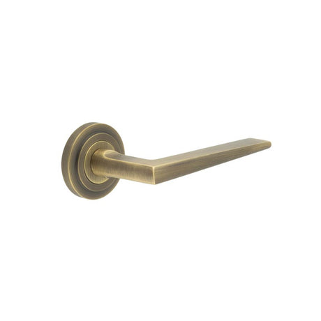 This is an image showing the Frelan - Mayfair Door Handle on Stepped Rose Antique Brass available to order from T.H. Wiggans Ironmongery in Kendal