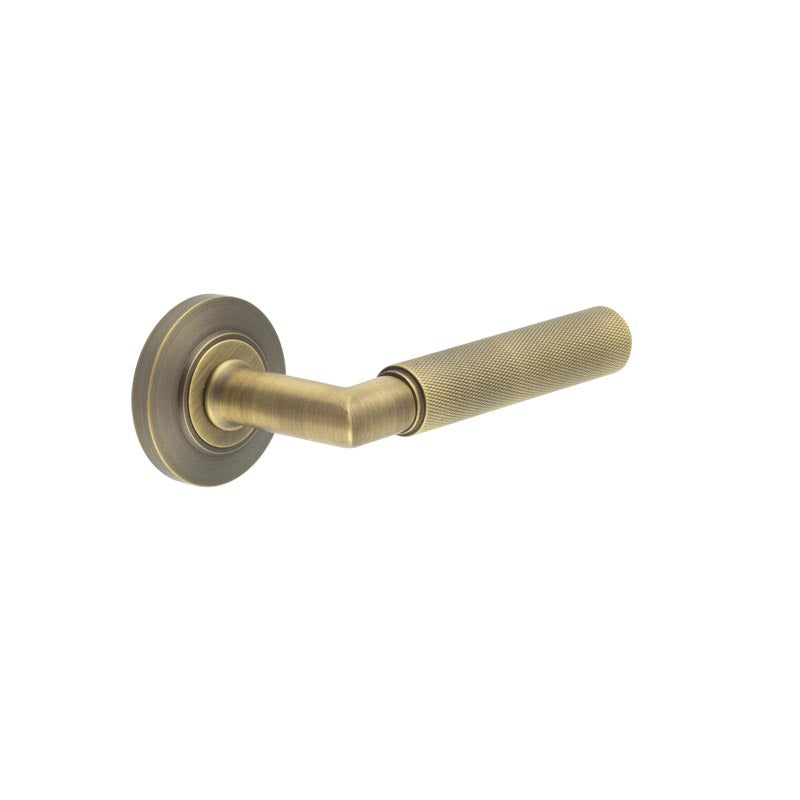 This is an image showing the Frelan - Piccadilly Door Handle on Chamfered Rose Antique Brass available to order from T.H. Wiggans Ironmongery in Kendal