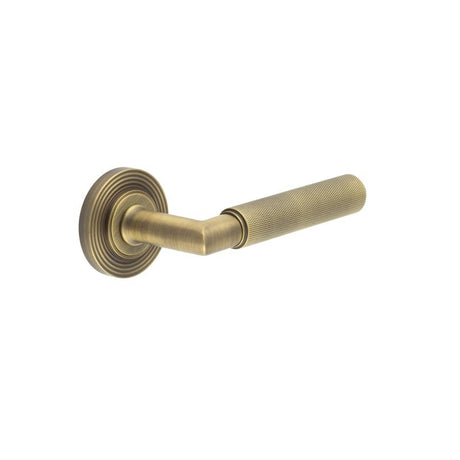 This is an image showing the Frelan - Piccadilly Door Handle on Reeded Rose Antique Brass available to order from T.H. Wiggans Ironmongery in Kendal