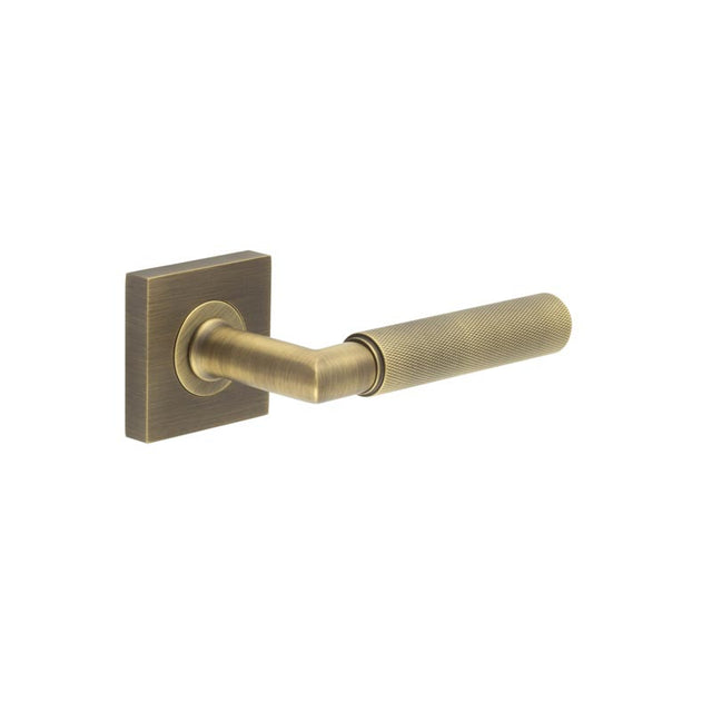 This is an image showing the Frelan - Piccadilly Door Handle on Square Plain Rose Antique Brass available to order from T.H. Wiggans Ironmongery in Kendal