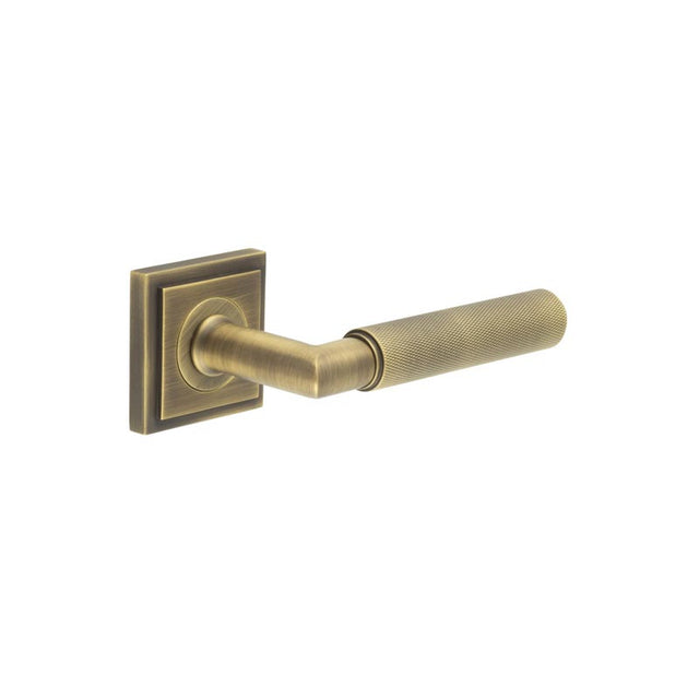 This is an image showing the Frelan - Piccadilly Door Handle on Stepped Square Rose Antique Brass available to order from T.H. Wiggans Ironmongery in Kendal