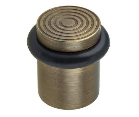 This is an image showing the Burlington - Floor mounted Door Stop - Antique Brass available to order from T.H. Wiggans Ironmongery in Kendal