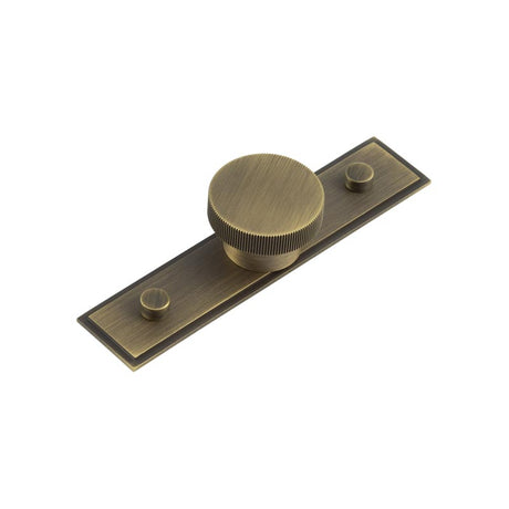 This is an image showing the Frelan - Thaxted Cupboard Knobs 40mm Stepped Backplate Antique Brass available to order from T.H. Wiggans Ironmongery in Kendal