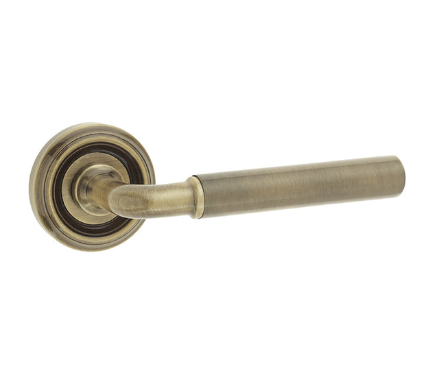 This is an image showing the Frelan - Elise Levers on Round Rose - Antique Brass available to order from T.H. Wiggans Ironmongery in Kendal