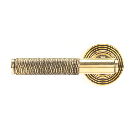 This is an image showing From The Anvil - Aged Brass Brompton Lever on Rose Set (Beehive) available from trade door handles, quick delivery and discounted prices