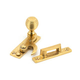 This is an image showing From The Anvil - Polished Brass Beehive Sash Hook Fastener available from T.H Wiggans Architectural Ironmongery in Kendal, quick delivery and discounted prices