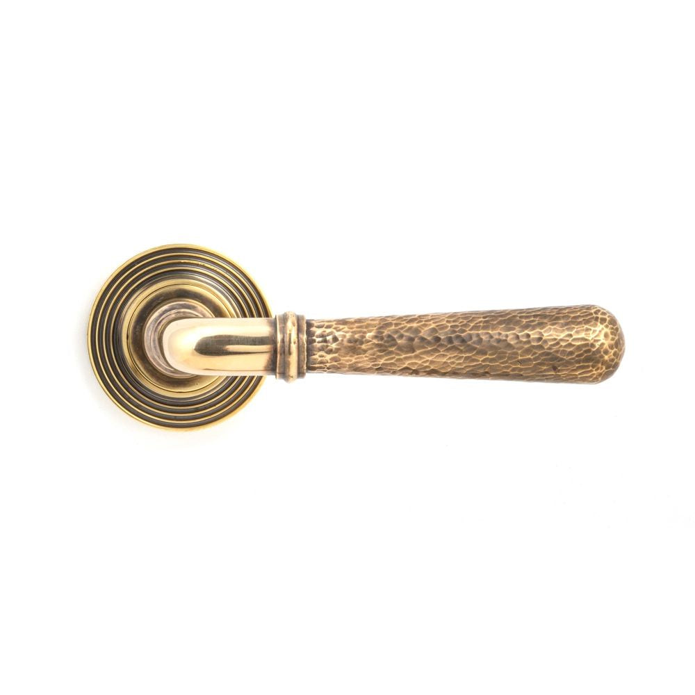 This is an image showing From The Anvil - Aged Brass Hammered Newbury Lever on Rose Set (Beehive) available from trade door handles, quick delivery and discounted prices