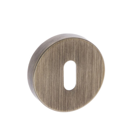 This is an image of Forme Key Escutcheon on Minimal Round Rose - Yester Bronze available to order from T.H Wiggans Architectural Ironmongery in Kendal, quick delivery and discounted prices.