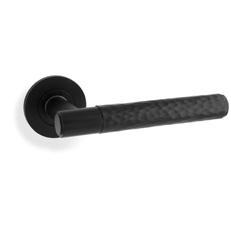This is an image showing Alexander & Wilks Spitfire Hammered Lever on Round Rose - Black aw223bl available to order from T.H Wiggans Ironmongery in Kendal, quick delivery and discounted prices.
