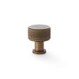 This is an image showing Alexander & Wilks Lucia Knurled Cupboard Knob - Antique Brass - 29mm aw807k-29-ab available to order from T.H Wiggans Ironmongery in Kendal, quick delivery and discounted prices.