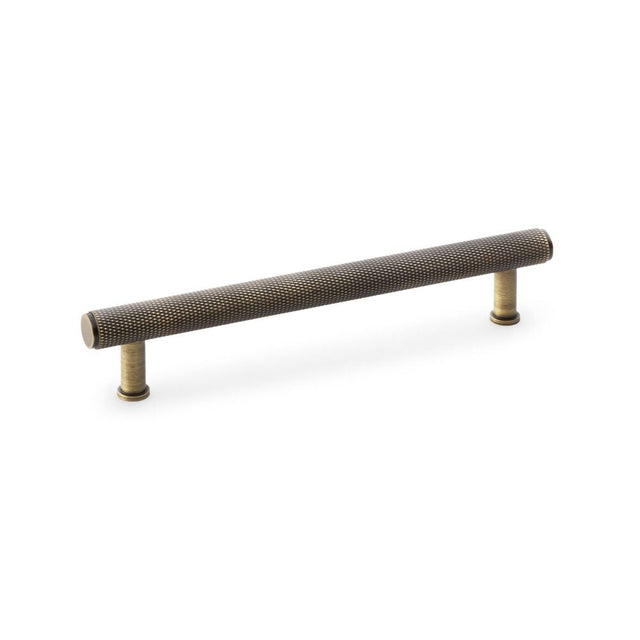 This is an image showing Alexander & Wilks Crispin Knurled T-bar Cupboard Pull Handle - Antique Brass - Centres 160mm aw809-160-ab available to order from T.H Wiggans Ironmongery in Kendal, quick delivery and discounted prices.