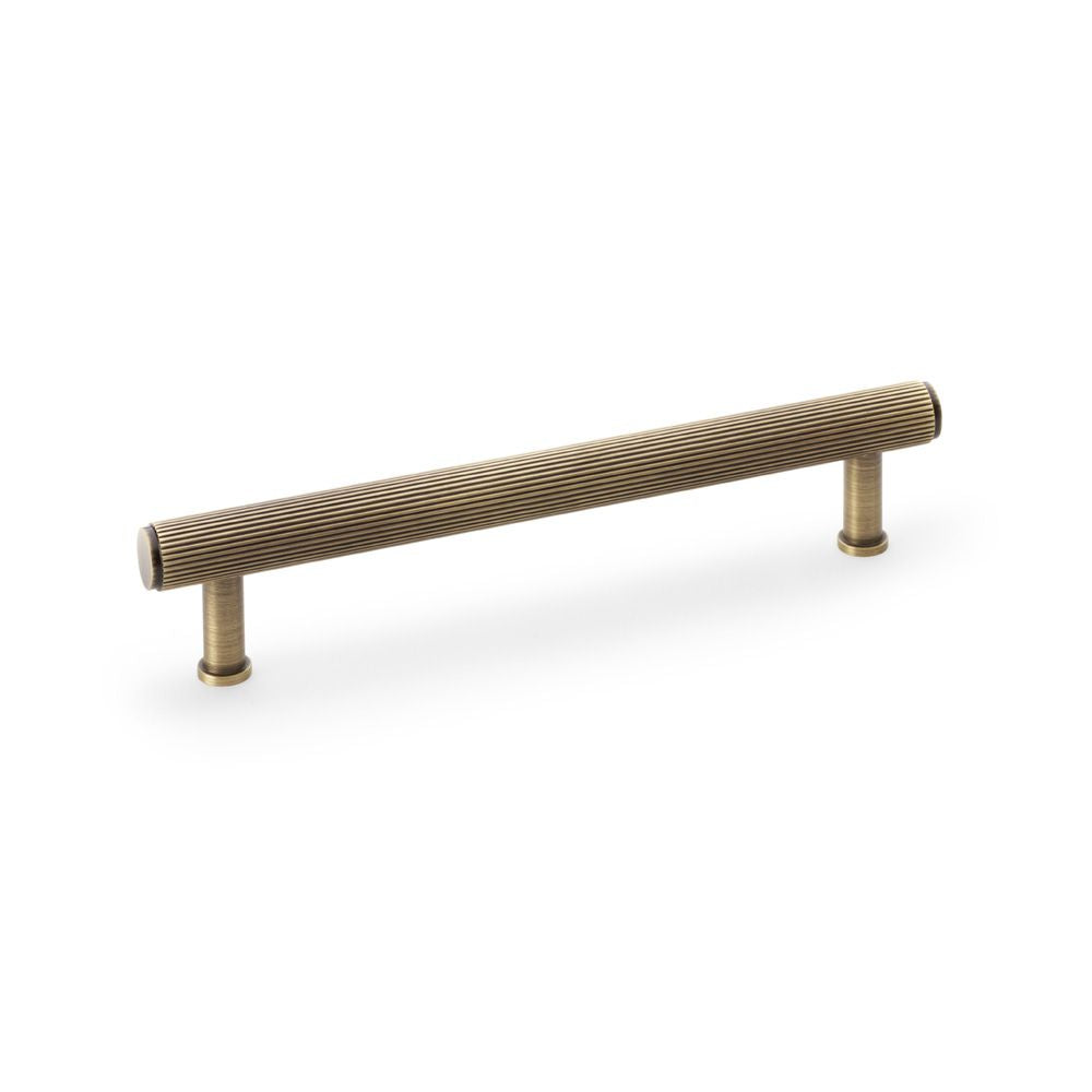 This is an image showing Alexander & Wilks Crispin Reeded T-bar Cupboard Pull Handle - Antique Brass - 160mm aw809r-160-ab available to order from T.H Wiggans Ironmongery in Kendal, quick delivery and discounted prices.