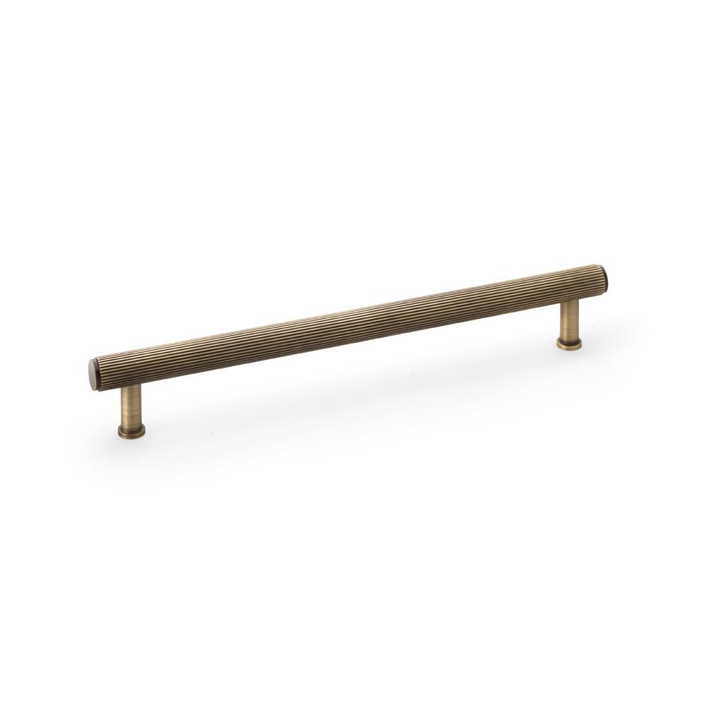 This is an image showing Alexander & Wilks Crispin Reeded T-bar Cupboard Pull Handle - Antique Brass - 224mm aw809r-224-ab available to order from T.H Wiggans Ironmongery in Kendal, quick delivery and discounted prices.