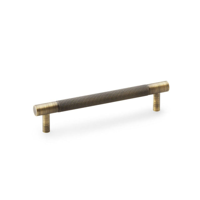 This is an image showing Alexander & Wilks Brunel Knurled T-Bar Cupboard Handle - Antique Brass - Centres 128mm aw810-128-ab available to order from T.H Wiggans Ironmongery in Kendal, quick delivery and discounted prices.