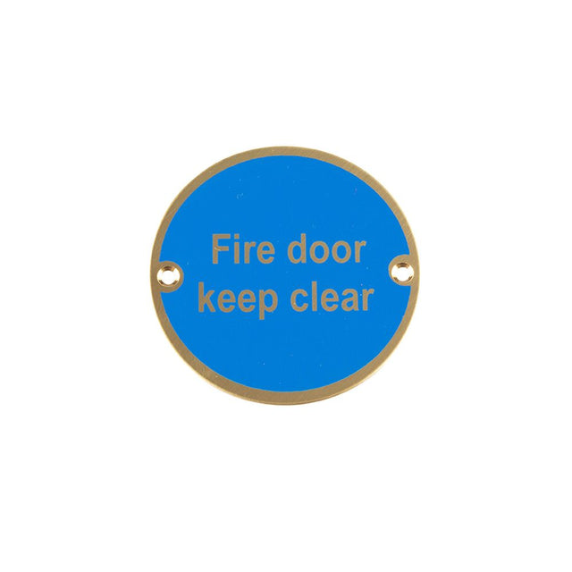 This is an image showing the Frelan - Fire Door Keep Clear - Signage 75mm Dia. - Polished Brass available to order from T.H. Wiggans Ironmongery in Kendal